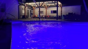 Uma área de piscina com um elemento aquático e um espaço coberto para sentar com luzes de corda.