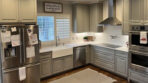 Uma cozinha moderna com eletrodomésticos de aço inoxidável, armários cinzas e painel de azulejos brancos.
