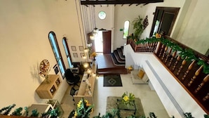 A spacious living area with a staircase, wooden beams, a sofa, a coffee table, and a plant. - Aguacatala Hotel Boutique (Medellín)