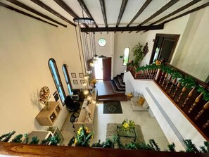 A spacious living area with a staircase, wooden beams, a sofa, a coffee table, and a plant. - Aguacatala Hotel Boutique (Medellín)