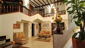 Amplia sala de estar con escalera, sofá, mesa de centro y una planta grande.