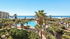 Ein Resort mit Pool, umgeben von Palmen und Blick auf den Ozean.