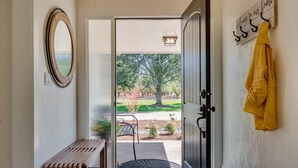 A hallway with a bench, a door leading outside, and a coat rack with a yellow garment.