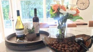 A kitchen counter with a wine bottle, a small potted plant, a vase with flowers, and a bowl of nuts.