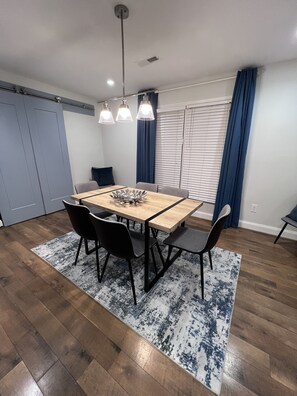 A dining area with a wooden table, black chairs, and a blue patterned rug.