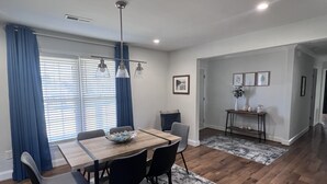 A modern dining area with a wooden table, black chairs, and a blue rug. - Modern Home (Mauldin)