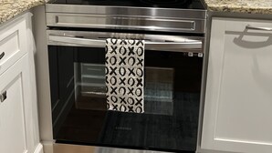 A kitchen with a stainless steel microwave, oven, and a digital clock displaying 19:45. - Modern Home (Mauldin)