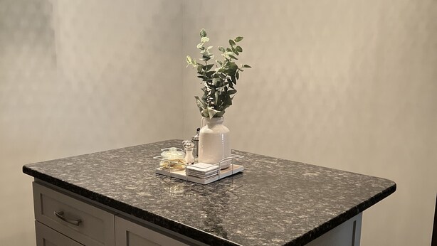 A kitchen with a granite countertop, a white vase with a plant, and three pendant lights. - Modern Home (Mauldin)