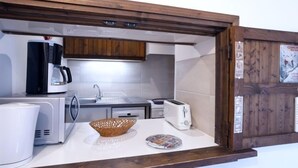 A compact kitchenette with a microwave, coffee maker, toaster, and a small sink.