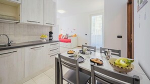 Een moderne keuken met witte kastjes, een eettafel gedekt met borden, glazen en een schaal fruit.