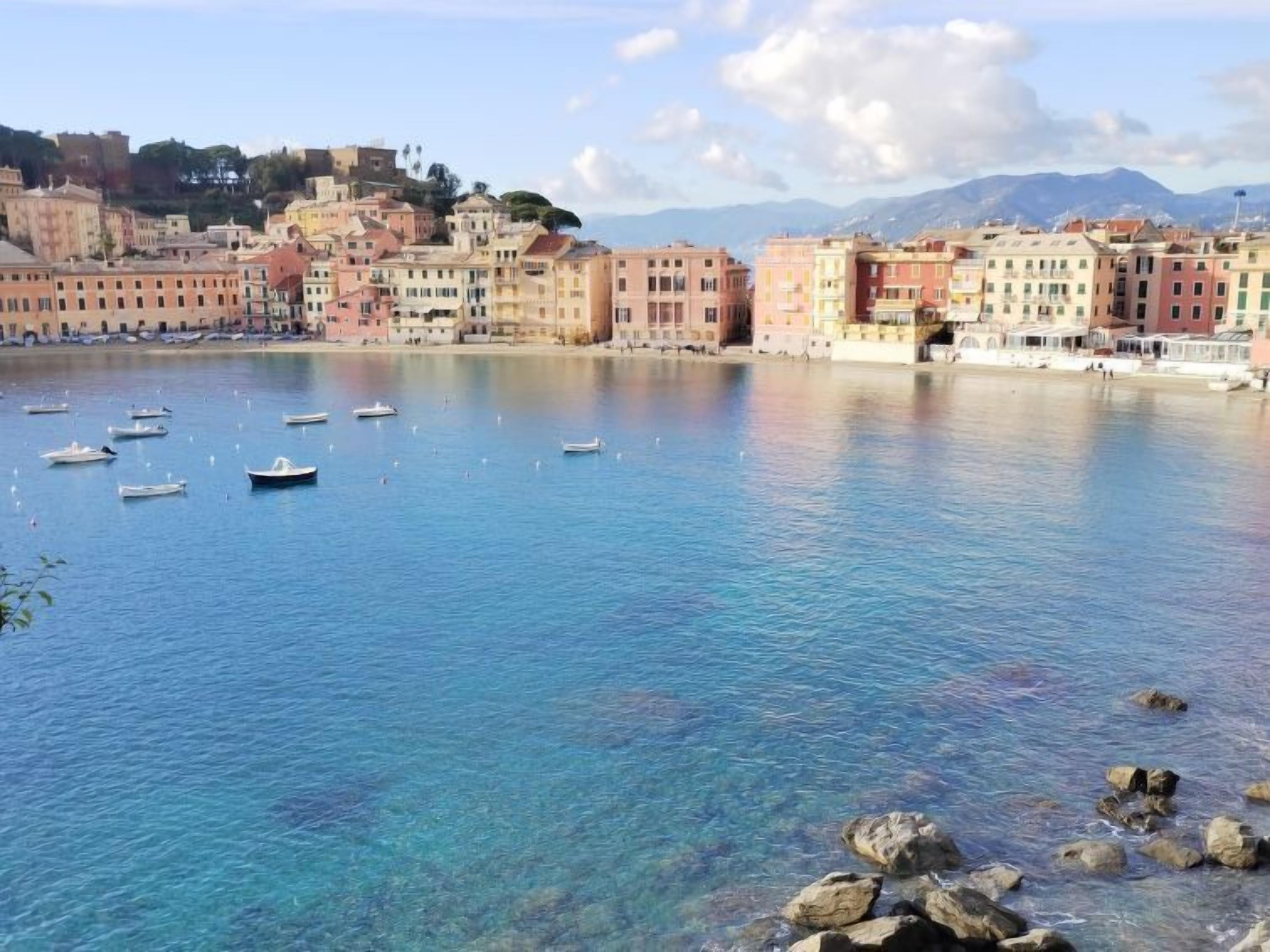 A coastal town with clear blue water, boats, and colorful buildings.