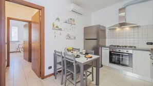 Een moderne keuken met een eethoek, met een koelkast van roestvrij staal, een fornuis en een betegelde spatwand.
