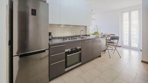 Een moderne keuken met roestvrijstalen apparatuur, witte kasten en een groot raam dat zorgt voor veel natuurlijk licht.