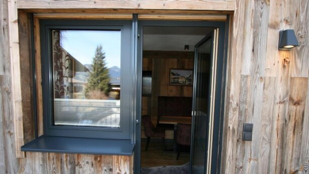 Ein Holzfassade mit einer Schiebetür aus Glas, die zu einem Innenraum führt.