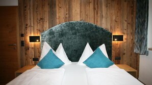 Ein Schlafzimmer mit Wandverkleidung aus Holz, einem großen Bett mit weißer Bettwäsche und blauen Kissen sowie zwei Wandleuchten.