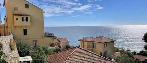 A coastal building with a tiled roof, a stone wall, and a view of the sea.