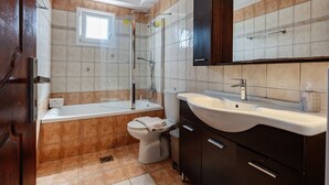 Une salle de bain comprenant une baignoire, des toilettes, un lavabo et un espace douche.