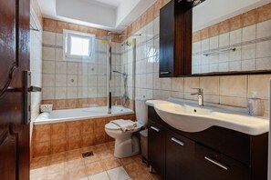 A bathroom with a bathtub, toilet, sink, and a shower area.