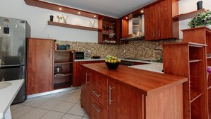 Une cuisine moderne avec des meubles en bois, un réfrigérateur en acier inoxydable, un four à micro-ondes et un pare-feu en carreaux.