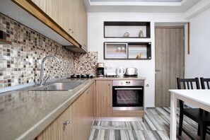 A modern kitchen with a tiled backsplash, stainless steel appliances, and a wooden cabinet.