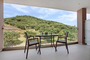 Un balcón con mesa y sillas, con vista a un paisaje montañoso.