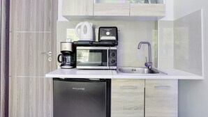 Una cocina compacta con lavavajillas PHILCO, cafetera, microondas y tostadora.