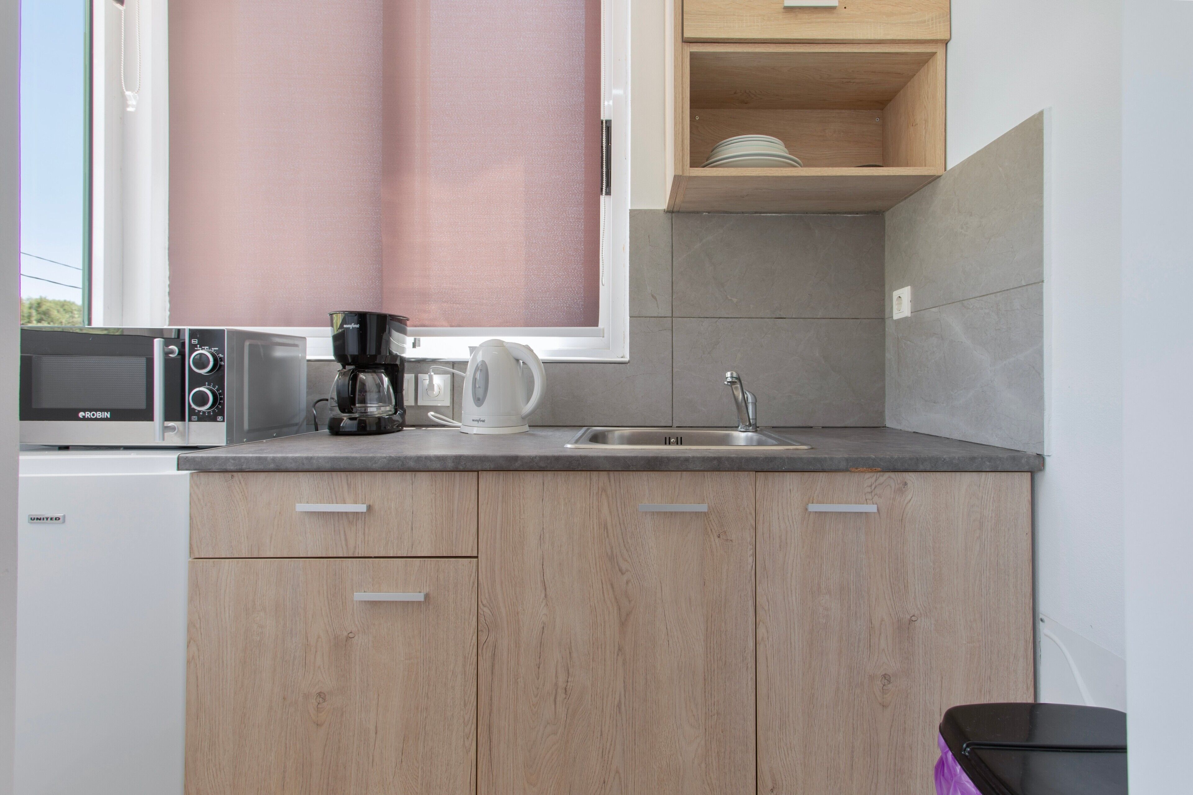 A kitchen with a microwave, coffee maker, and sink.
