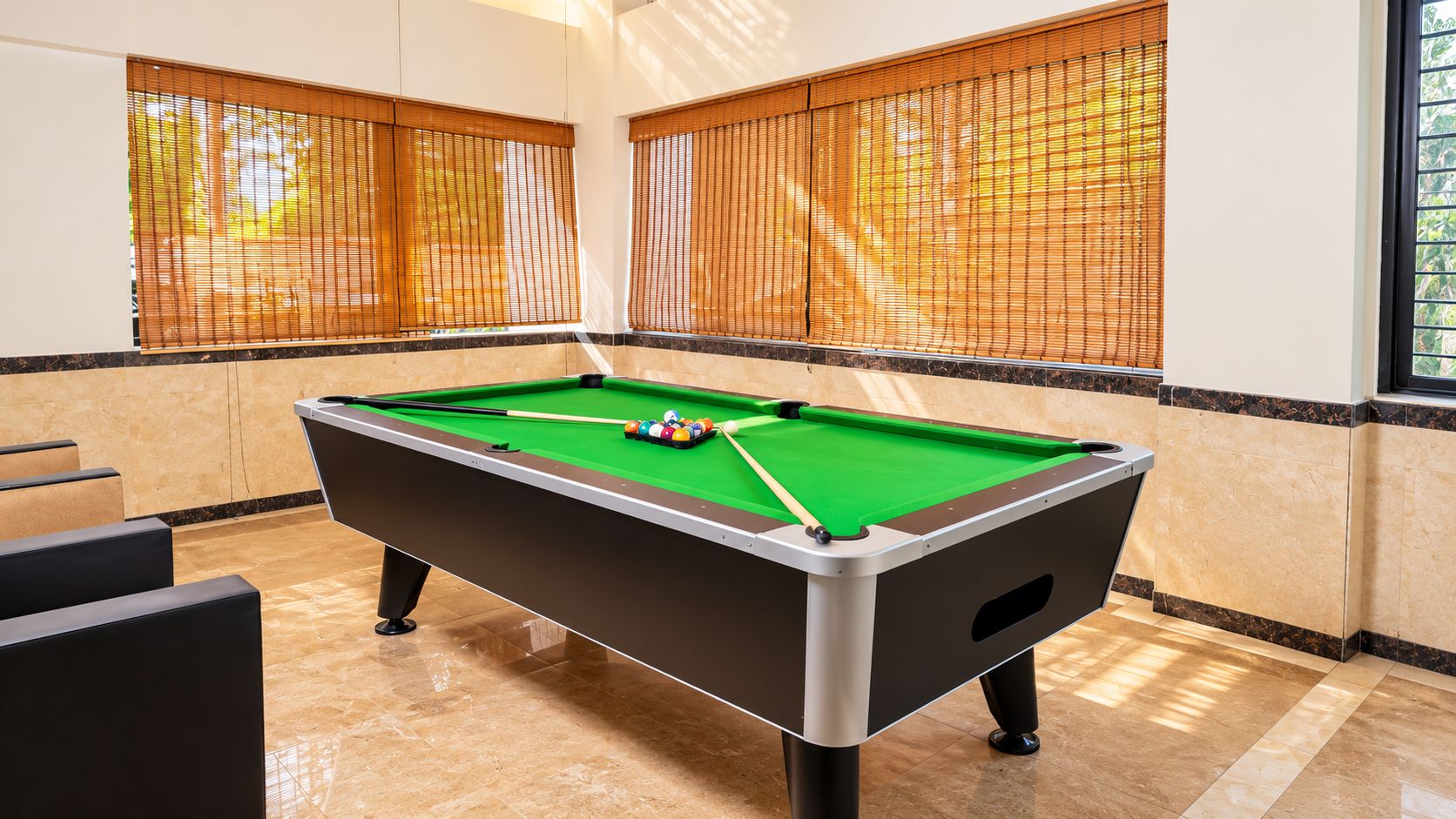 A pool table in a room with a marble floor and beige walls.