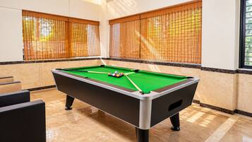 A pool table in a room with a marble floor and beige walls.