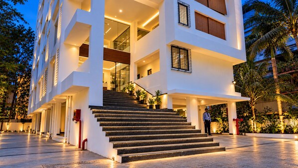 A multi-story hotel with a central staircase, outdoor lighting, and a security guard.