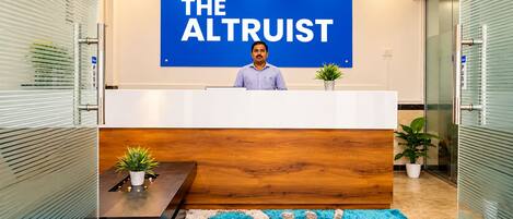Un mostrador de recepción con un cartel que dice 'THE ALTRUIT' y una persona sentada detrás.