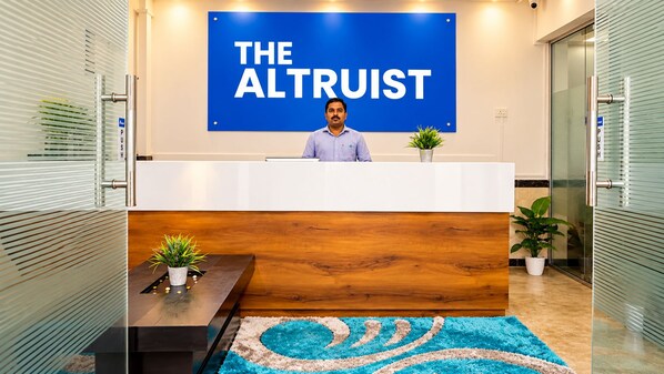 A reception desk with a sign reading 'THE ALTRUIT' and a person seated behind it.