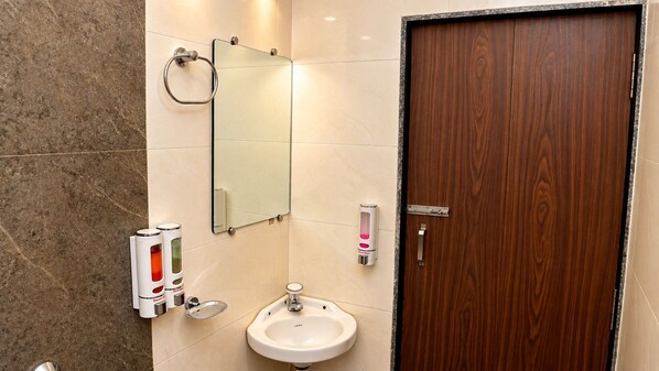 A bathroom with a wooden door, a mirror, a sink, and two soap dispensers. - The Altruist Koparkhairane Hotel (Navi Mumbai)