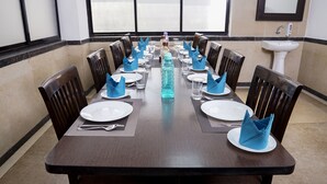 A dining table set for a meal with blue napkins, white plates, and clear glasses. - The Altruist Koparkhairane Hotel (Navi Mumbai)