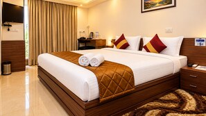 A hotel room with a large bed, a desk, a television, and a view of the outdoors.