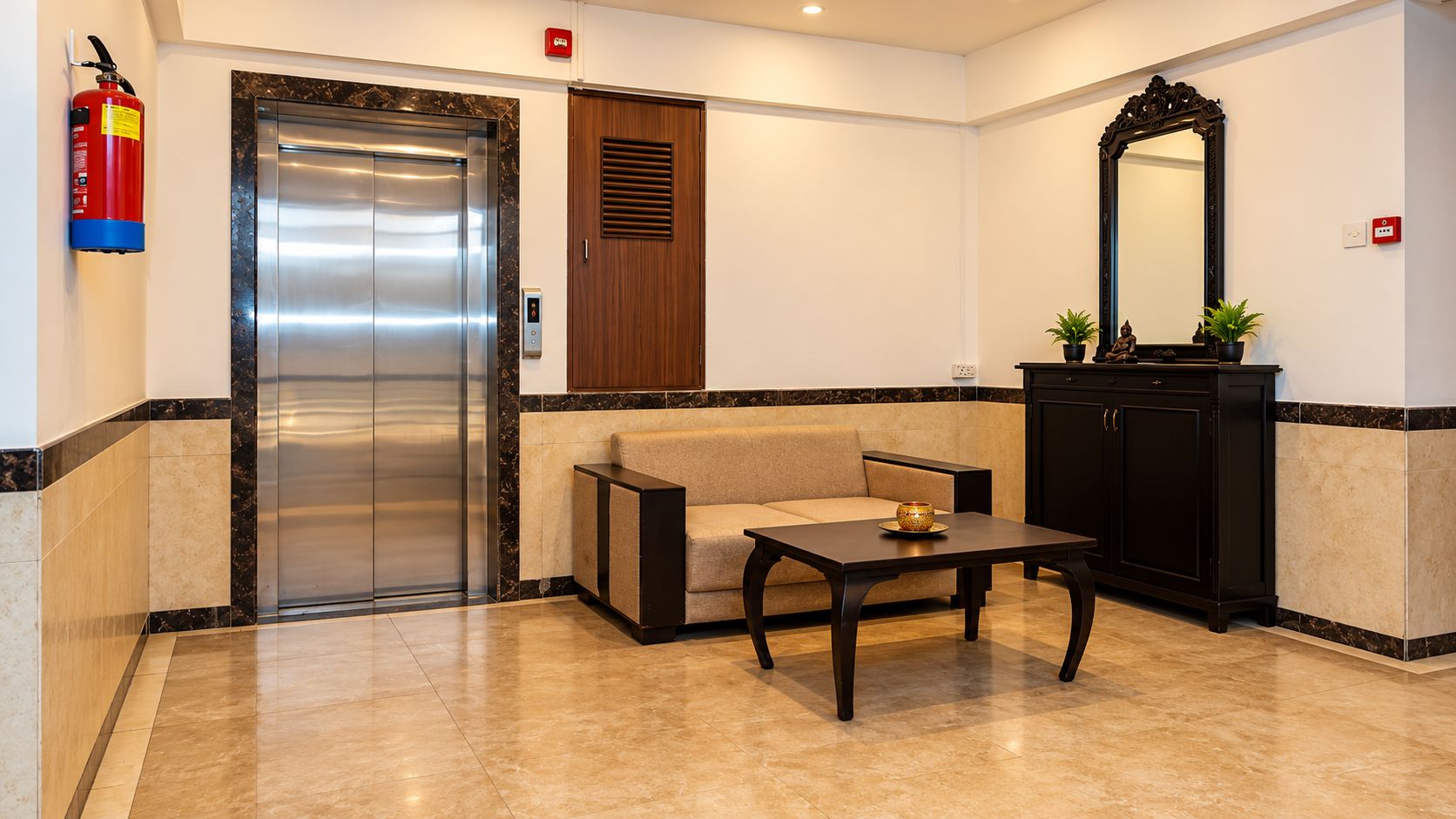 A lobby with a marble floor, a sofa, a table, a cabinet, a mirror, and an elevator.