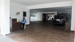 A spacious indoor area with a tiled floor, a desk with a chair, and a parked car. - The Altruist Koparkhairane Hotel (Navi Mumbai)
