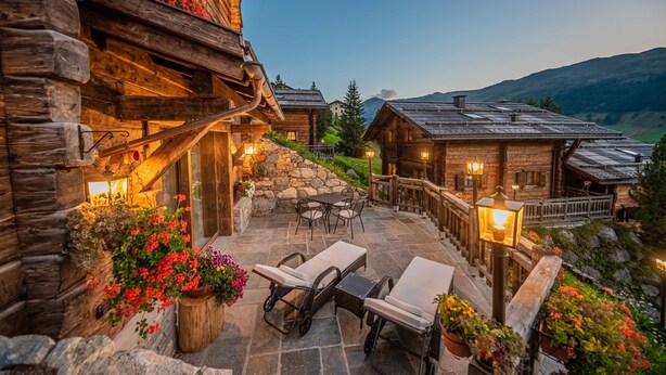 A log cabin with a stone patio, outdoor seating, and a view of the mountains. - 'Le Chalet Suite' with mountain view, private terrace and Wi-Fi (Livigno)