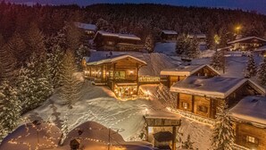 A snow-covered village with wooden cabins, illuminated by warm lights, surrounded by trees. - 'Le Chalet Suite' with mountain view, private terrace and Wi-Fi (Livigno)