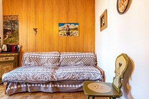 Une pièce avec un mur lambrissé en bois, un lit avec une literie à motifs, une petite table et une chaise.
