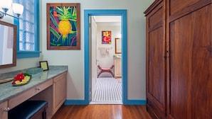 A hallway with a wooden bench, a counter with a fruit bowl, and a door leading to a bathroom.