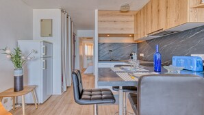 Eine moderne Küche mit Marmorarbeitsplatte, Holzschränken und einem Essbereich mit Tisch und Stühlen.