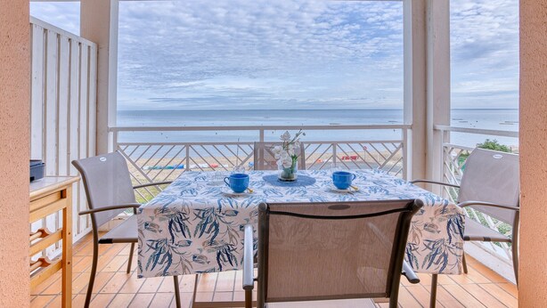Ein Balkon mit Tisch und Stühlen mit Blick auf das Meer.