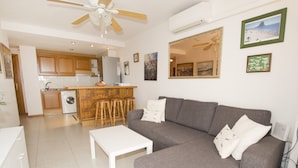 A living room with a grey sofa, a white coffee table, and a kitchen area in the background. - A102 CALPPLACE 2-5º-2 (Calpe)