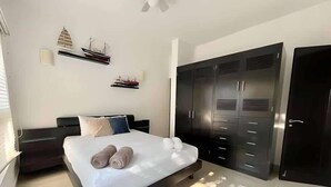 Une chambre à coucher moderne, avec un lit, une armoire et un petit modèle de bateau décoratif accroché au mur.