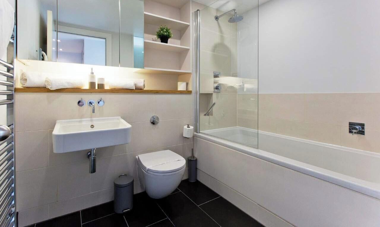 A modern bathroom with a white sink, toilet, and glass-enclosed shower.