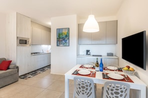 A modern kitchen with a microwave, dining table set with plates, cutlery, and a bottle.