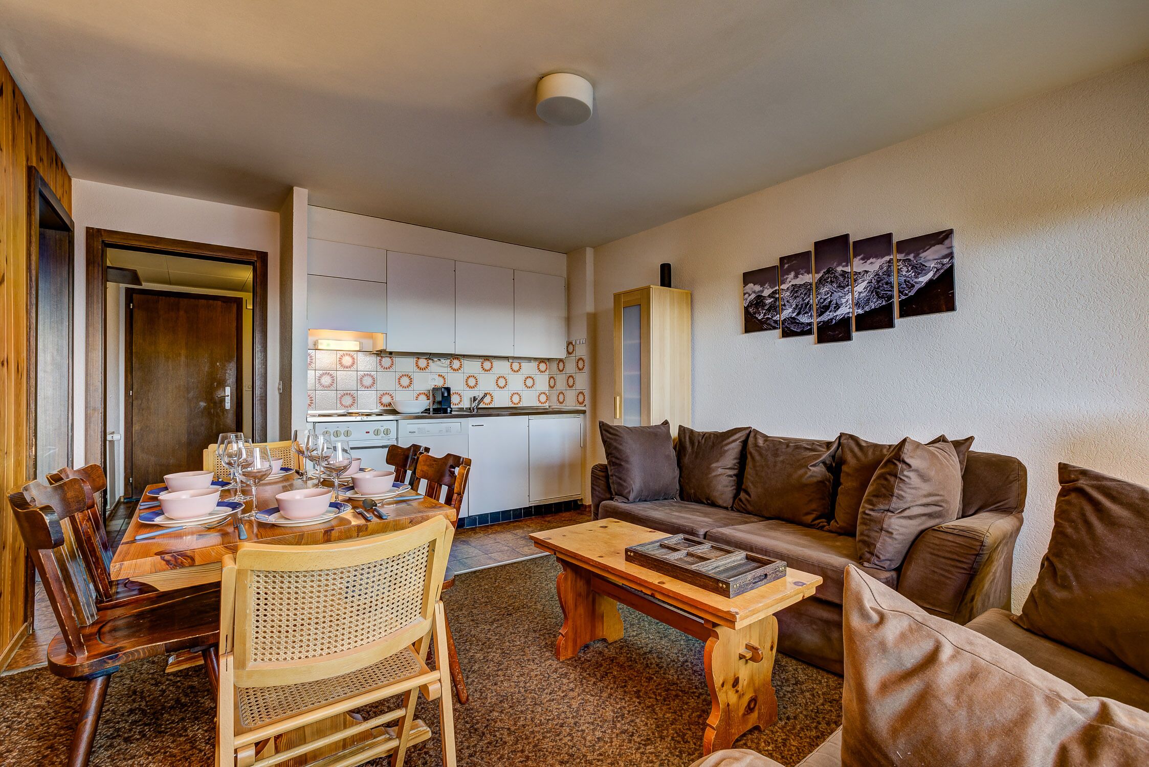 A compact living space with a dining area, a sofa, and a kitchen.