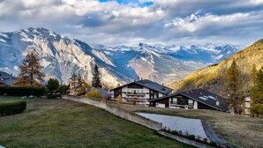 A mountain house with a view of snow-capped peaks, a paved driveway, and a small lawn area. - Appartement LaForet 23 - La Tzoumaz, 4 Vallees (La Tzoumaz)