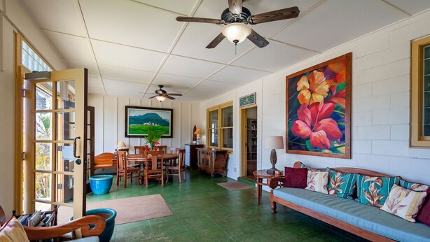 A spacious living area with a dining set, a sofa, and a ceiling fan.